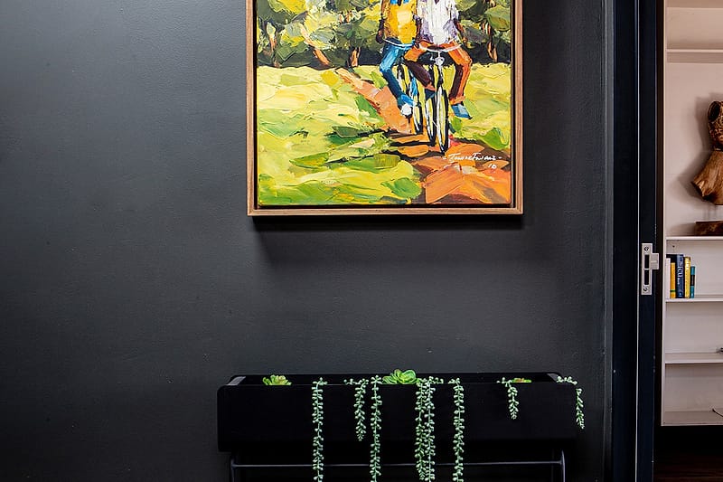 A dark console table with trailing plants and a carved wooden figure on the shelf above.
