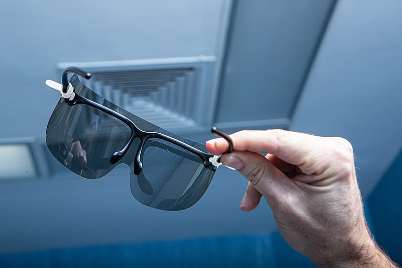 A surgeon's hand holding a pair of protective loupes before a case.